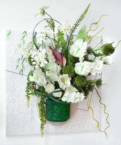 Bouquet of white flowers in a green vase on a textured white background